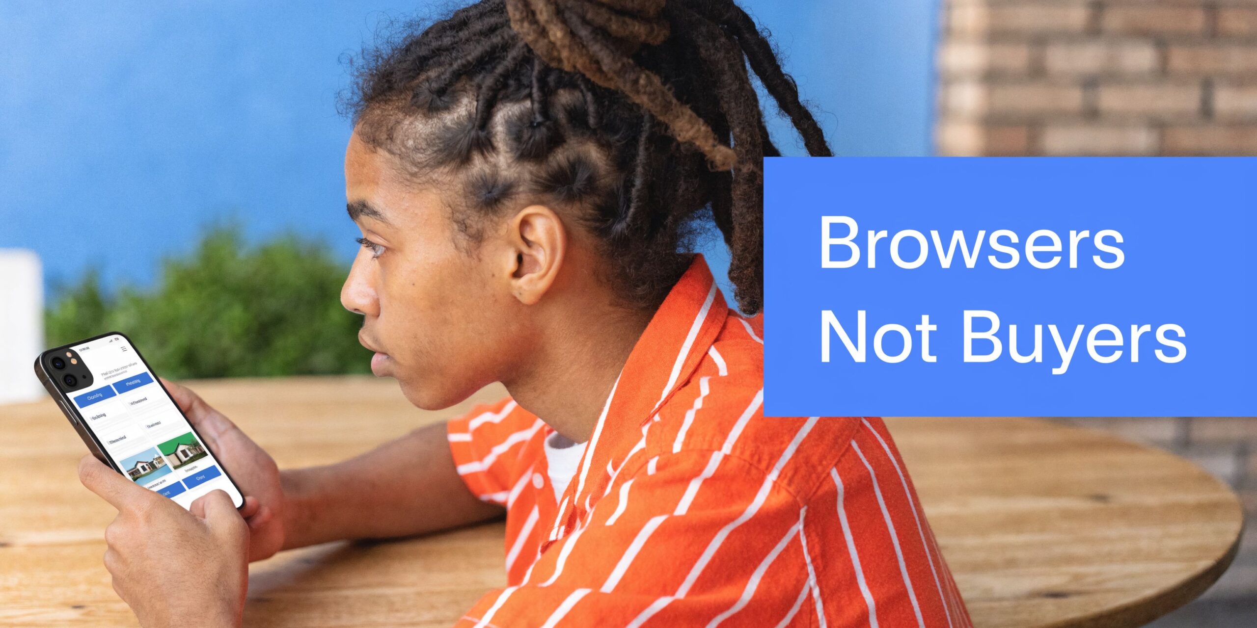 A young person with dreadlocks looking at real estate listings on a smartphone while sitting outside.